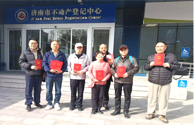 首批中部分住户拿着刚刚办好的不动产权证在济南市不动产登记中心前合影